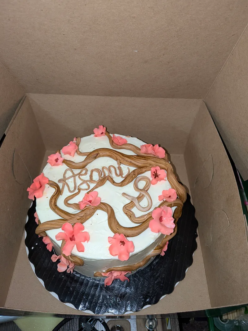 White cake decorated with a piped branch and coral blossoms