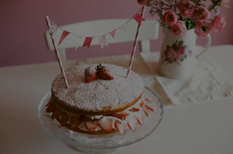 Powdered-sugar sponge cake with strawberries and a small bunting topper