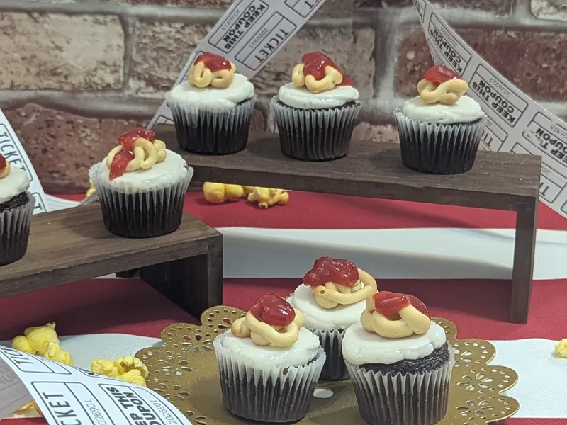 Themed cupcakes on a wooden stand with popcorn and ticket-ribbon props