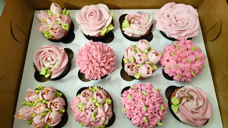 Box of cupcakes piped as pink roses, carnations and tulips