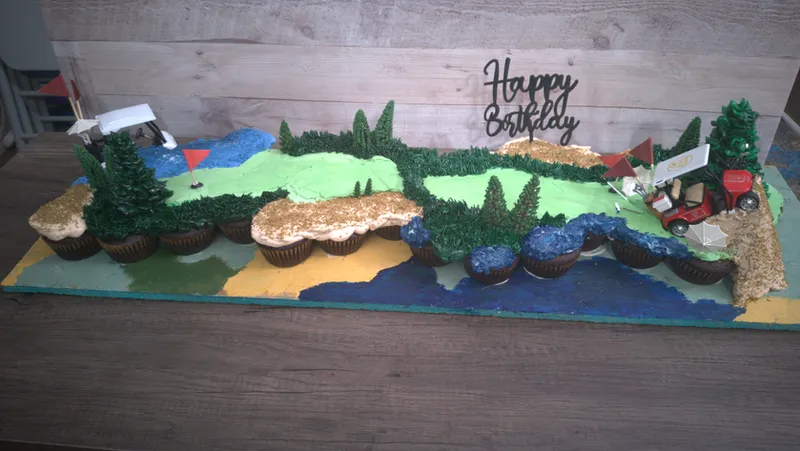 Pull-apart cupcake cake shaped as a green landscape with trees and a Happy Birthday topper
