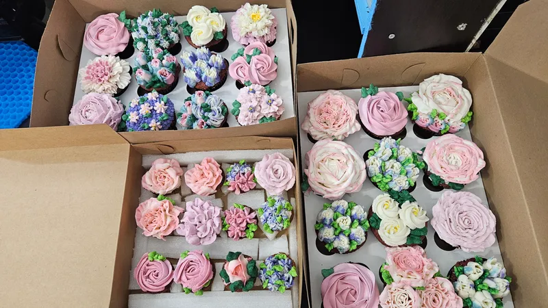 Two boxes of floral cupcakes in pinks, blues and whites